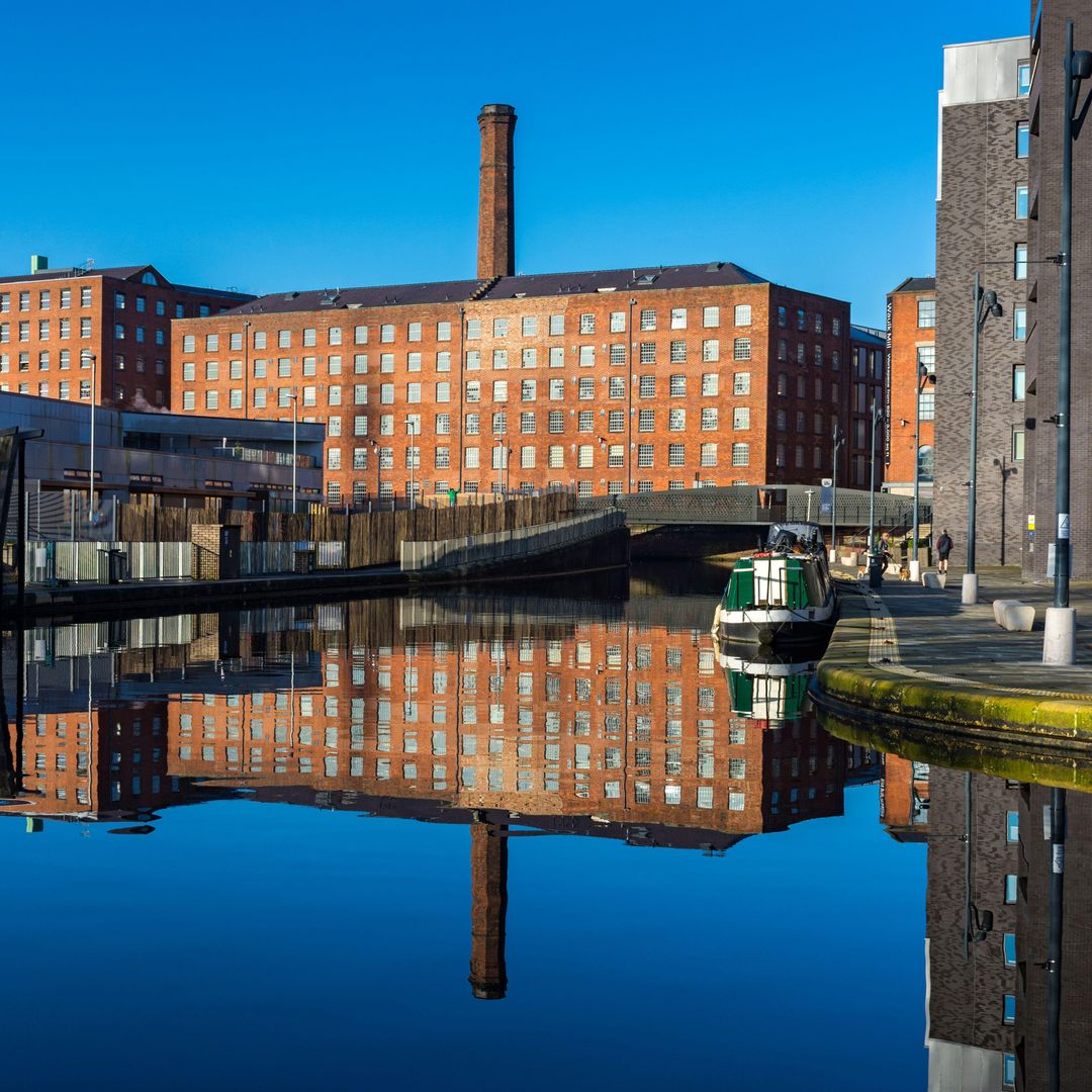 Los molinos de Murrays reflejados en el agua del puerto deportivo de Cotton Field, en New Islington, Ancoats, Mánchester, Inglaterra, Reino Unido.