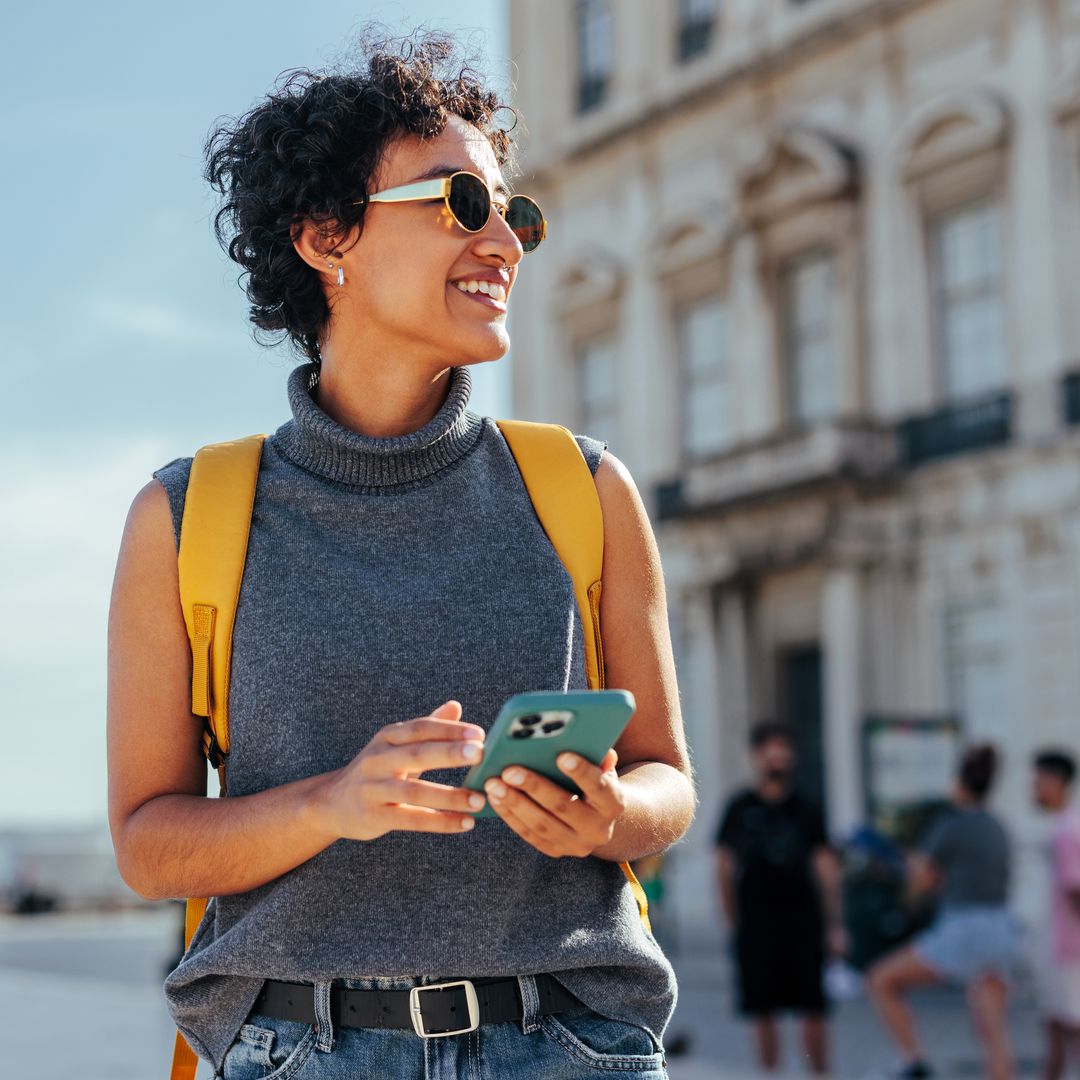 Una mujer joven explora una ciudad con su teléfono móvil en la mano