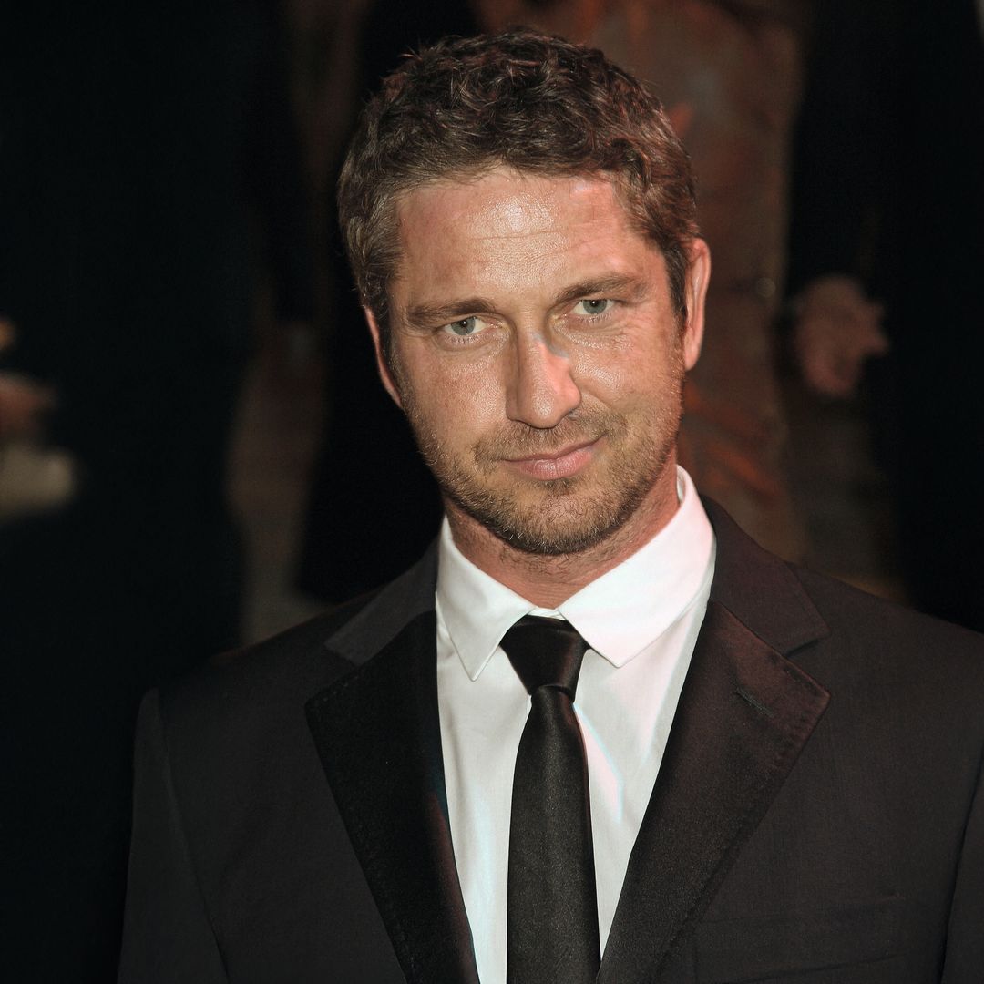 Gerard Butler en traje negro, camisa blanca y corbata negra