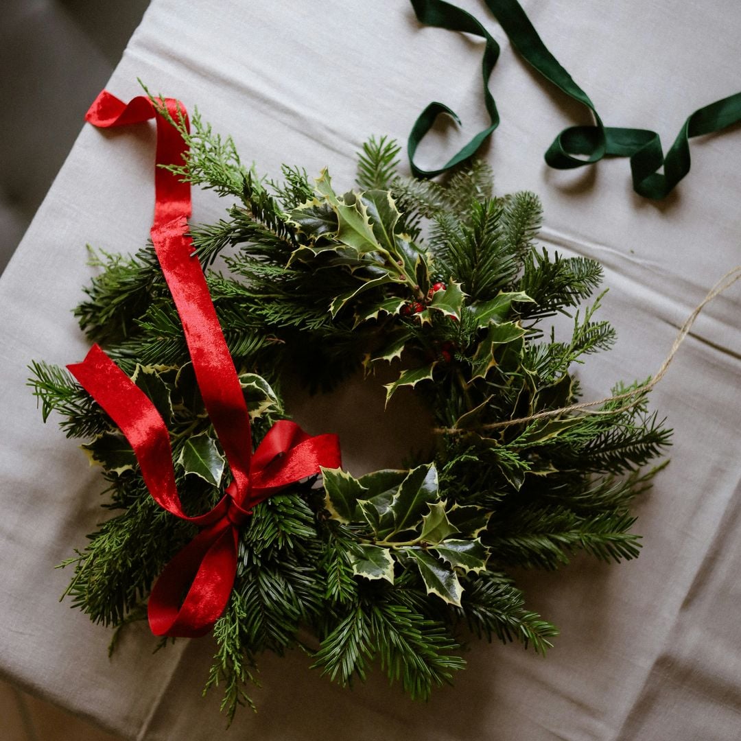 Corona de adviento como centro de mesa en verde y rojo con acebo.