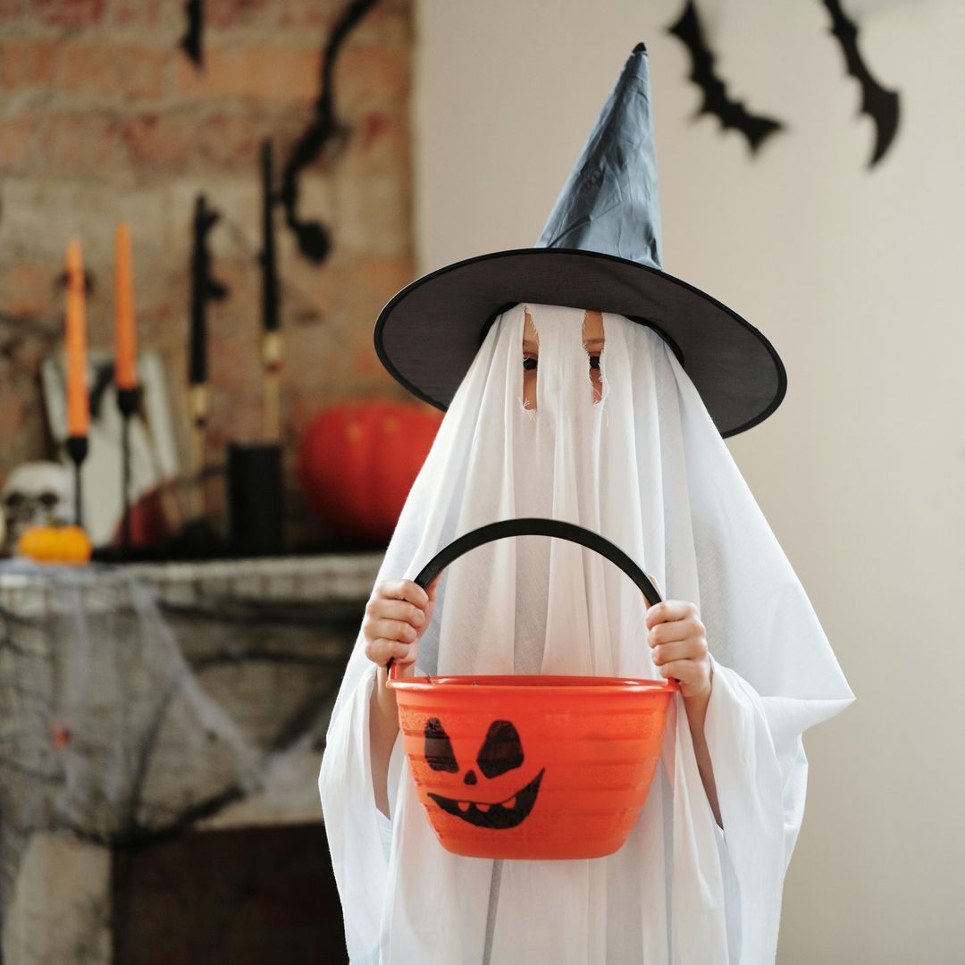 Niño disfrazado de fantasma con una calabaza entre las manos por Halloween