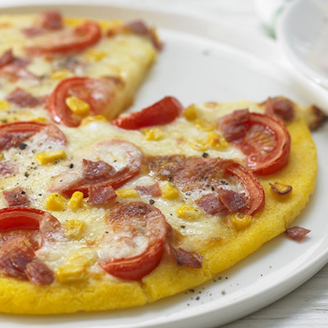 Pizza con base de polenta con salami, maíz y tomate