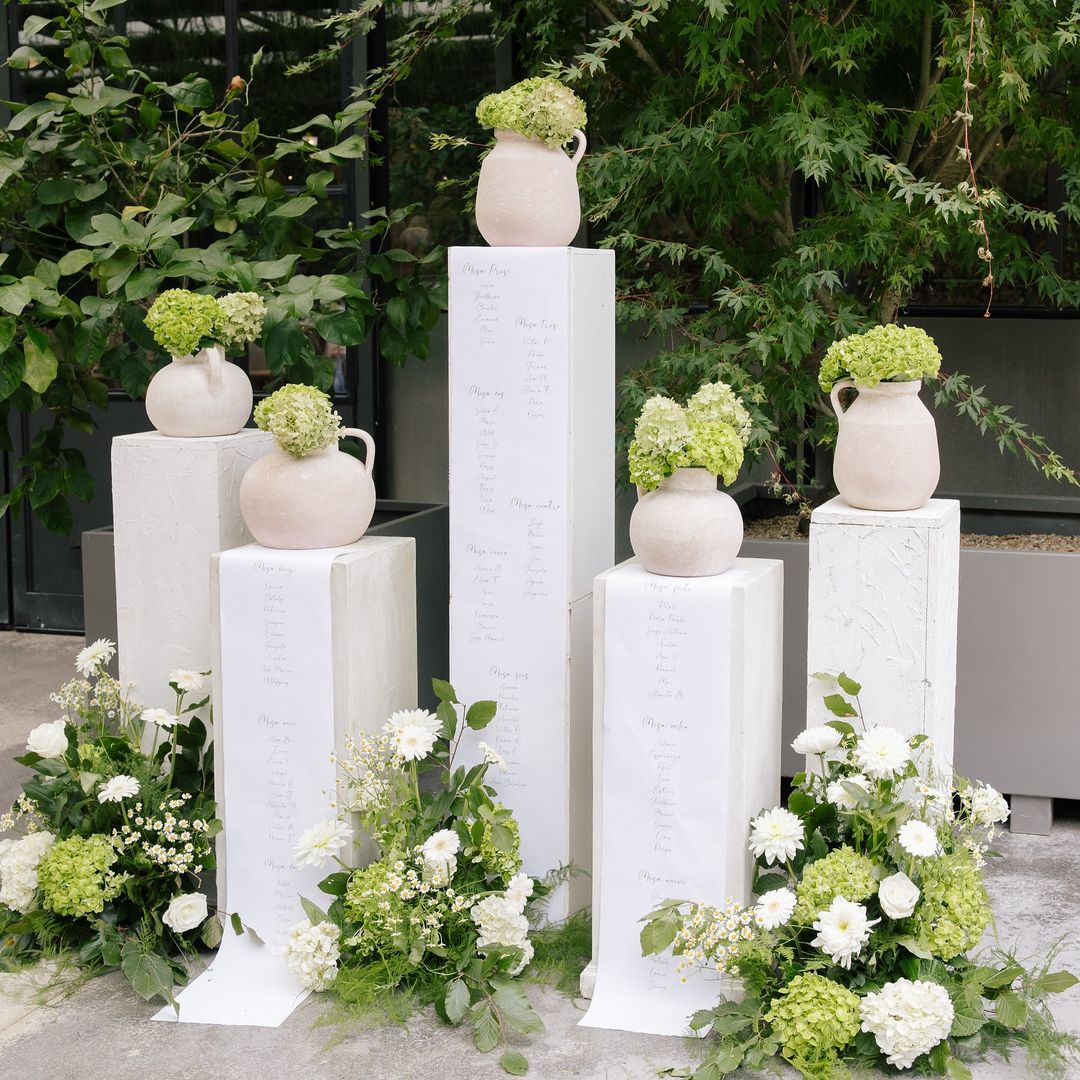 Seating plans de boda en columnas vasijas y flores verdes
