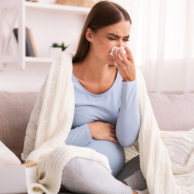 mujer embarazada con gripe sonandose la nariz