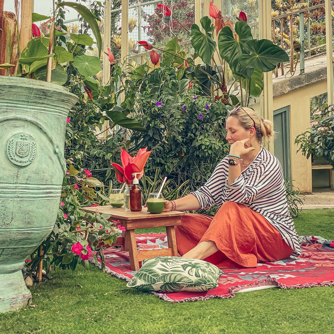 Mujer tomando una bebida vegetariana en un jardín tropical