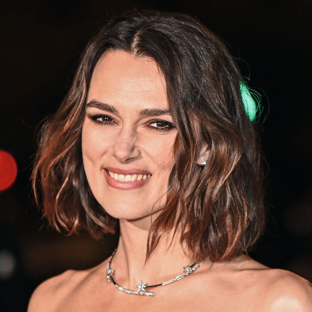 Keira Knightley sonriendo en un vestido negro con joyas