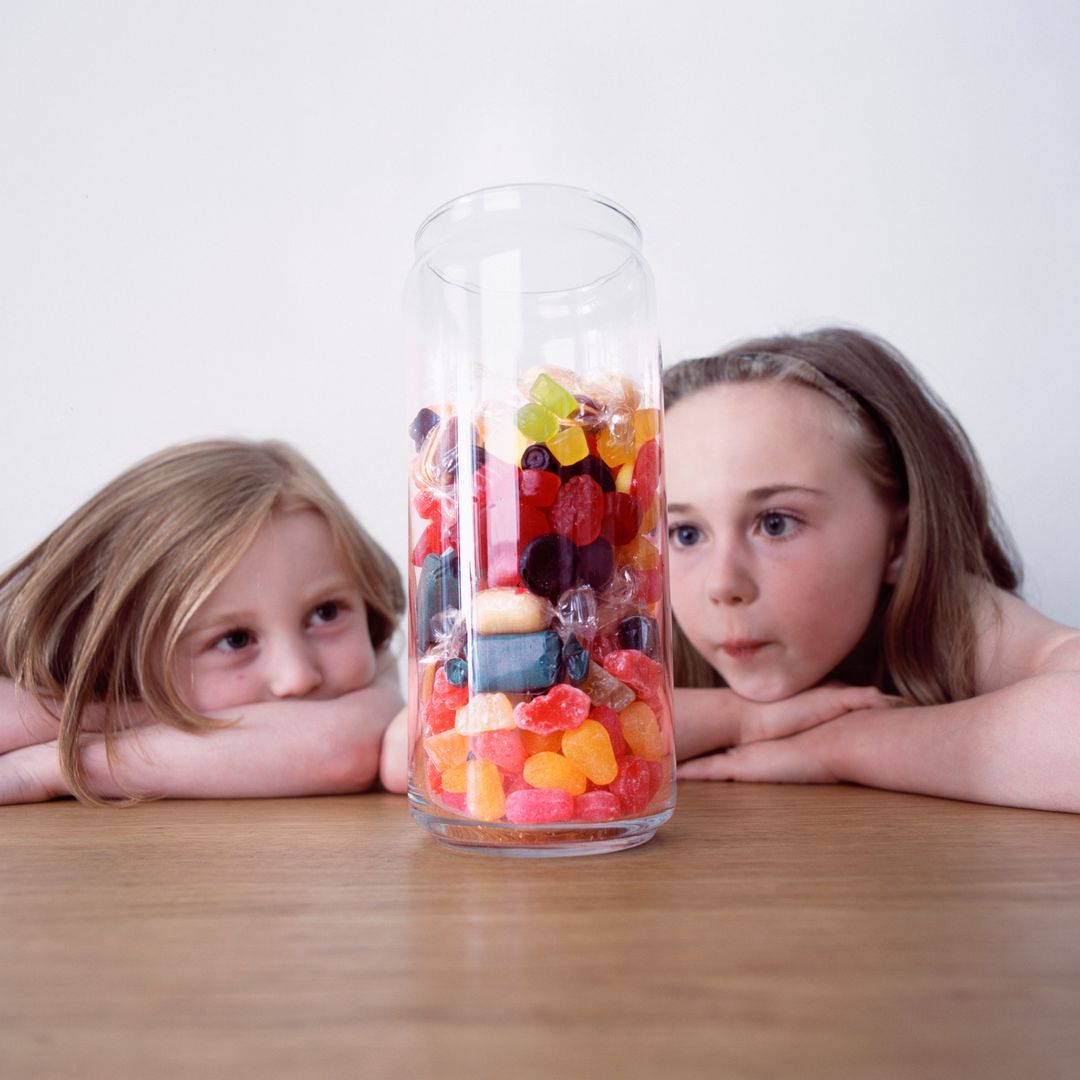 Niñas observan un bote lleno de chuches