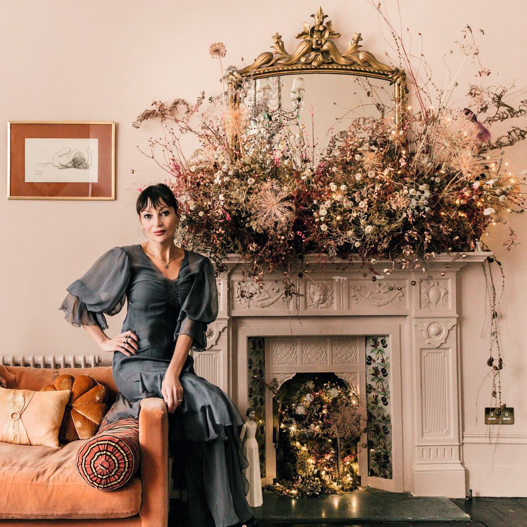 Pearl Lowe posa en una sala con chimenea decorada y sofá con cojines.