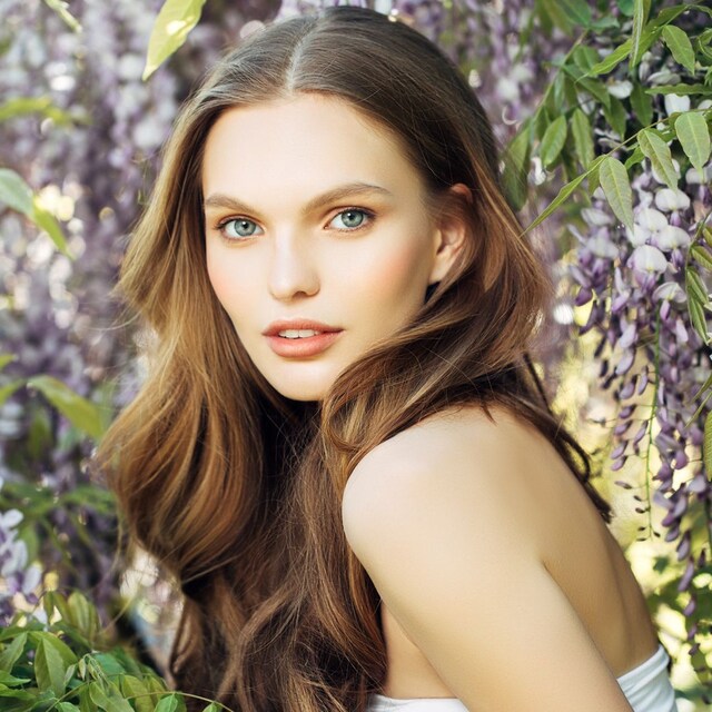 Mujer pelo suelto, castaño en un fondo de flores y naturaleza