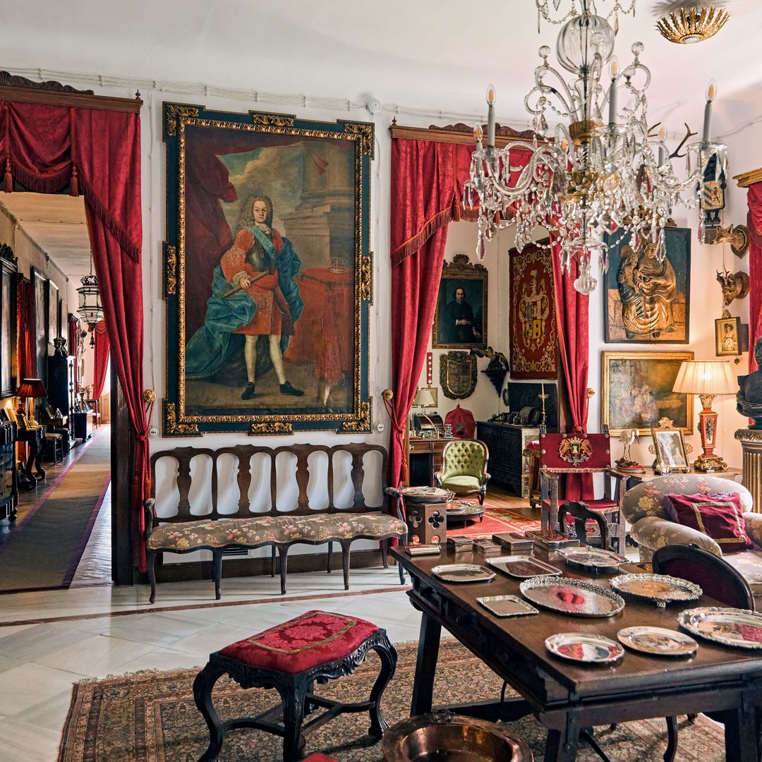Una foto de la misma estancia, en la que vemos distintos elementos decorativos: el retrato del Rey Francisco de Asís, su lámpara de cristal de La Granja —de finales del siglo XVIII— y un bajorrelieve de la virgen Santa Ana —del siglo XVI—.