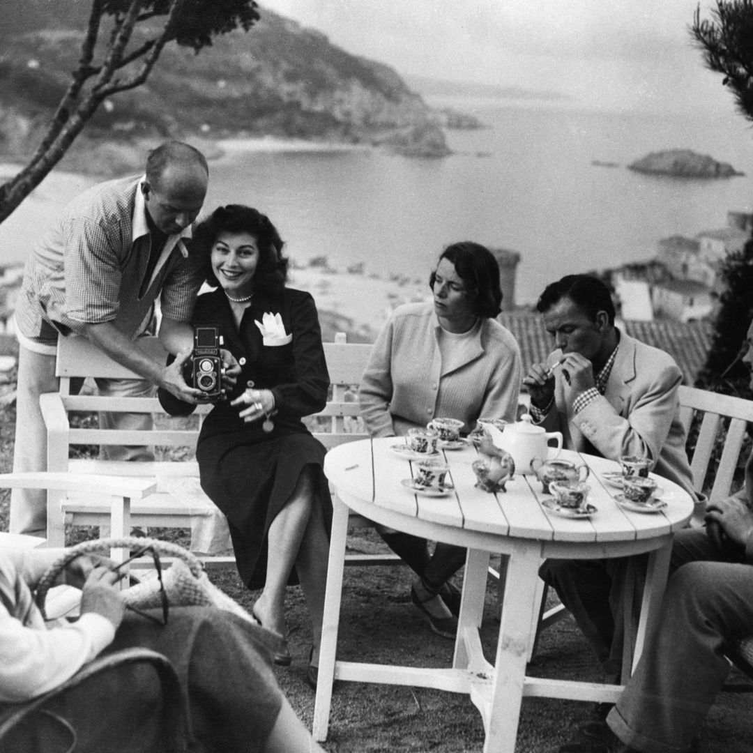 Frank Sinatra y Ava Gardner comparten un momento en un jardín con vistas a la Costa Brava, en España (1956), en plena etapa de su relación sentimental, rodeados de un ambiente íntimo y veraniego junto a otros acompañantes