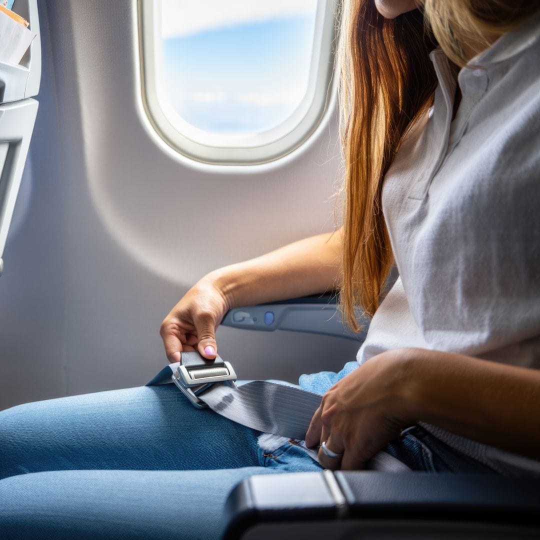 Mujer abrochándose el cinturón de seguridad en un avión