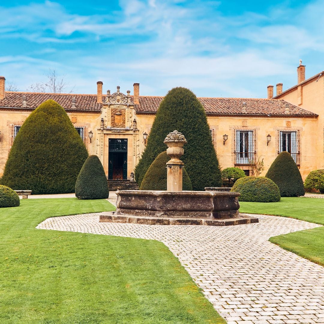 Una vista panorámica del palacio y su jardín, con sus frondosos tejos y su fuente octogonal