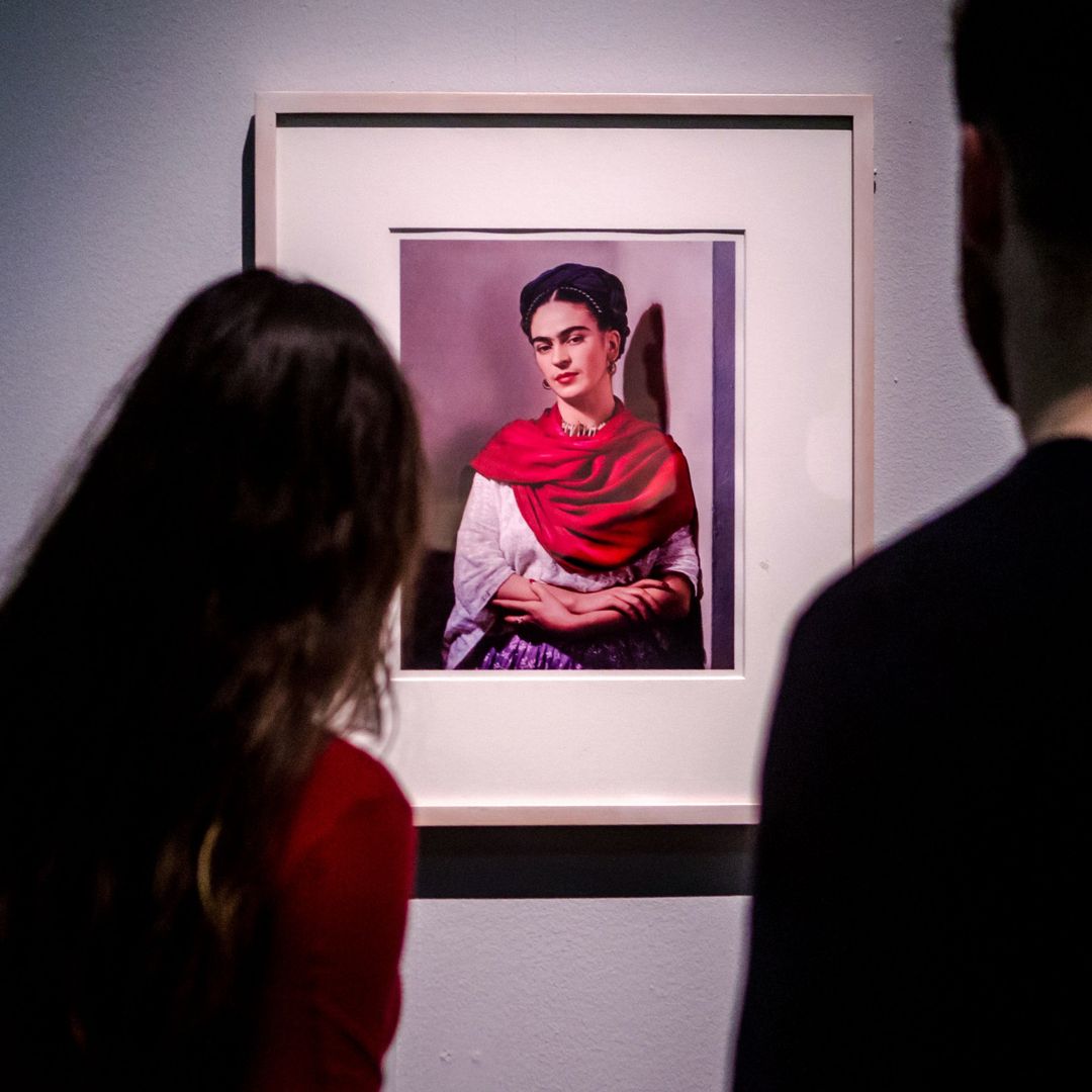 Dos personas miran un retrato de Frida