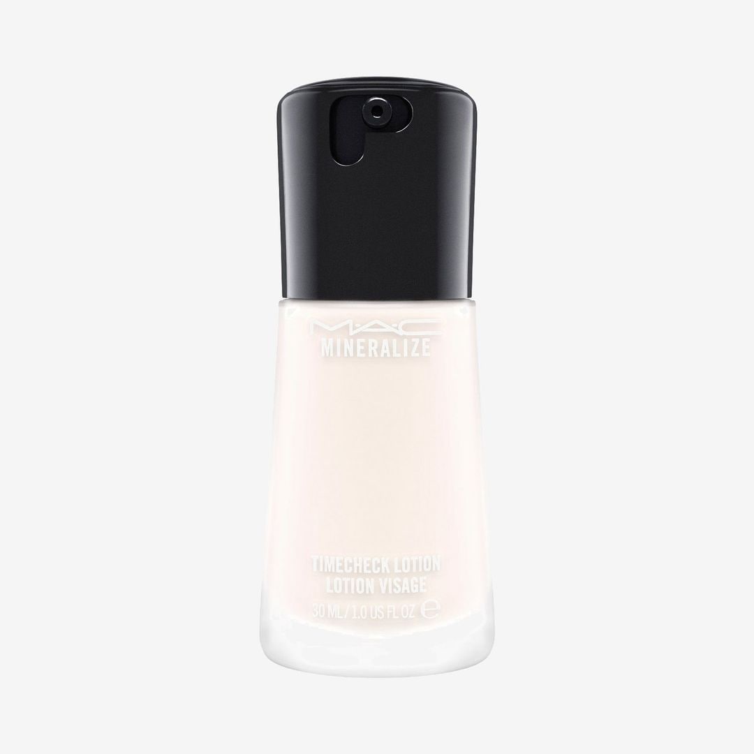 Botella del primer facial MAC Mineralize Timecheck Lotion con tapa negra y fórmula iluminadora.