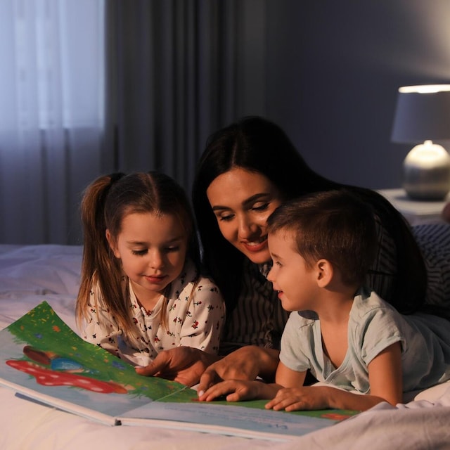 madre leyendo un cuento a sus hijos tumbados en la cama de su habitaci n