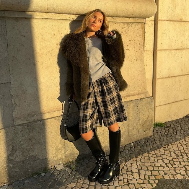 bermudas de tartan con botas altas negras y abrigo de pelo