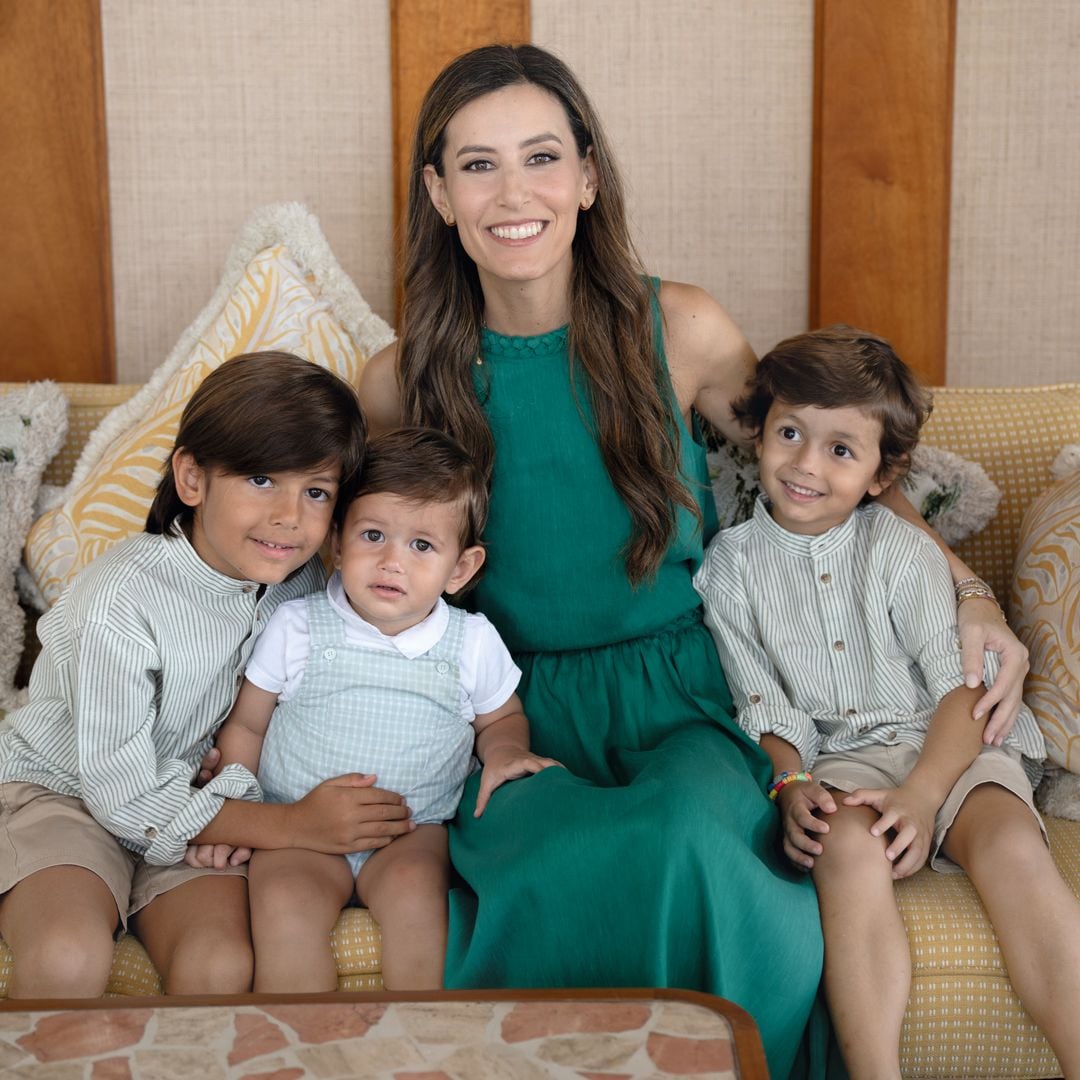 Ana Boyer con vestido largo verde sentada en un sofá con sus tres hijos