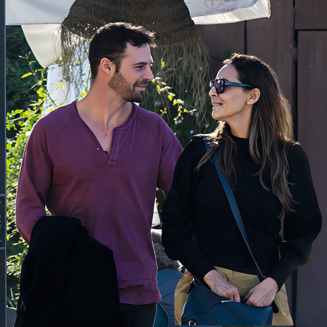 Eva González y Nacho Llanos conversando al aire libre, ella con gafas de sol y bolso azul.