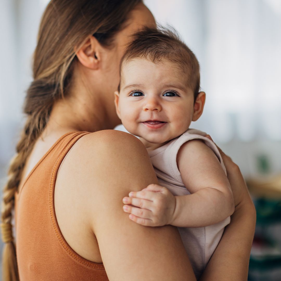 Bebé sonriente en brazos de su madre