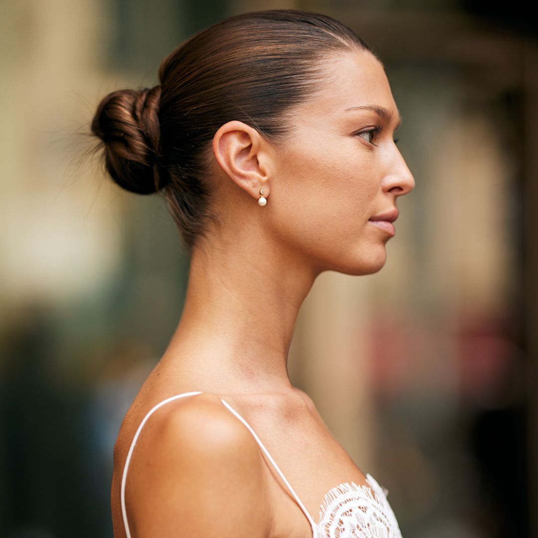 Mujer castaña de perfil con vestido blanco y recogido tirante