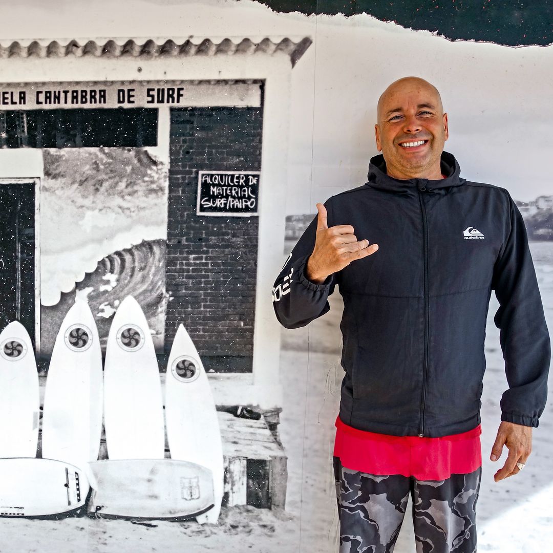 David García Capi, en la Escuela Cántabra de Surf, junto a una foto antigua de sus inicios, Somo, Cantabria
