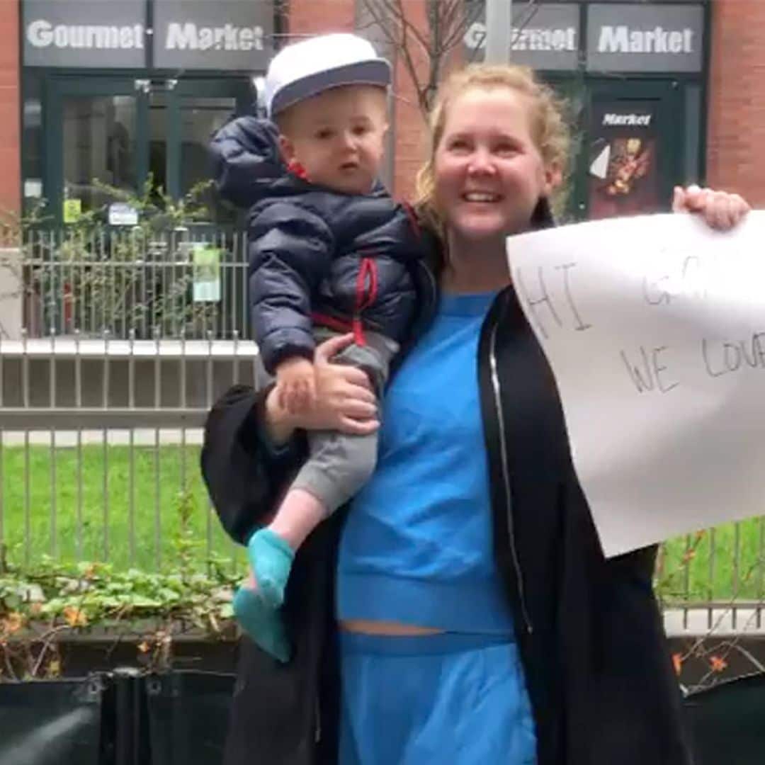 Con su hijo en un brazo y un cartel en otro, Amy Schumer envía ánimos a su padre desde la acera