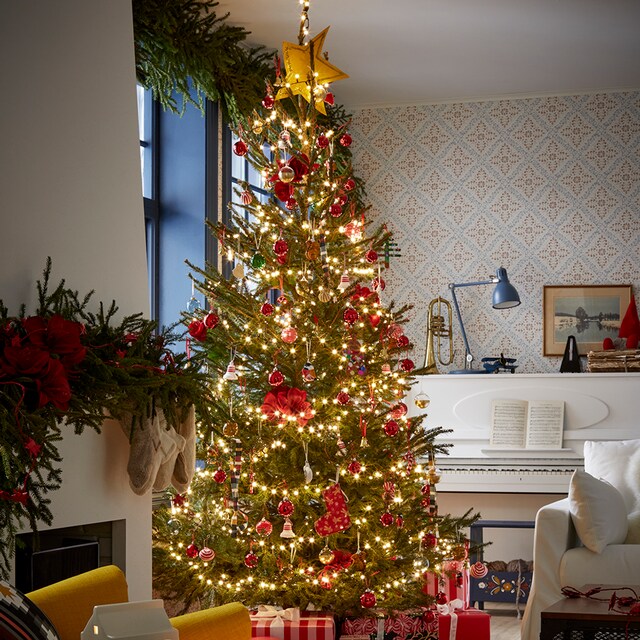 ´Salón con piano y chimenea y árbol de Navidad con guirnaldas de luces y regalos 