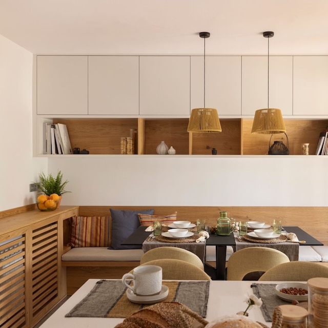 Comedor con banco de madera, estantería, tapa radiador de madera y lámparas de fibras 