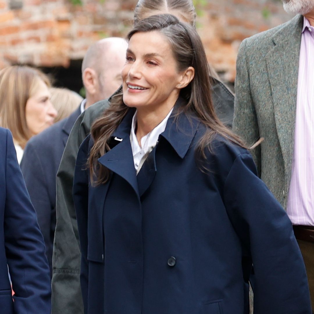 La reina Letizia sorprende con gabardina y el bajo deshilachado de sus vaqueros en su look más cercano y juvenil