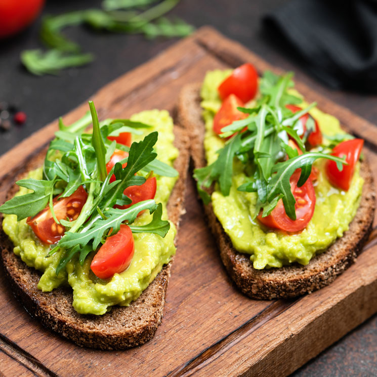 Tostadas integrales de aguacate, tomates y rúcula