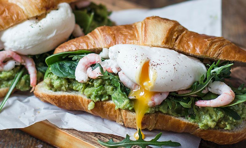 Croissant con aguacate, gambas y huevo poché