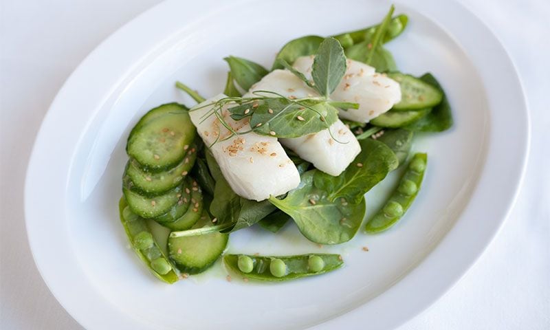 Ensalada de bacalao, pepino, guisantes y hojas verdes