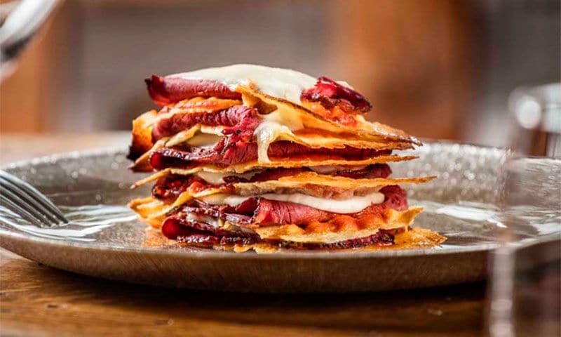 Milhojas de pan crujiente, queso y pastrami
