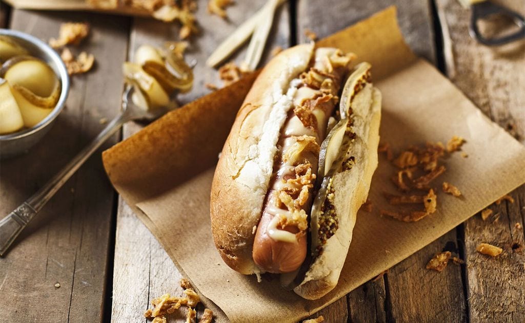 Perrito caliente con queso cheddar y cebolla crujiente