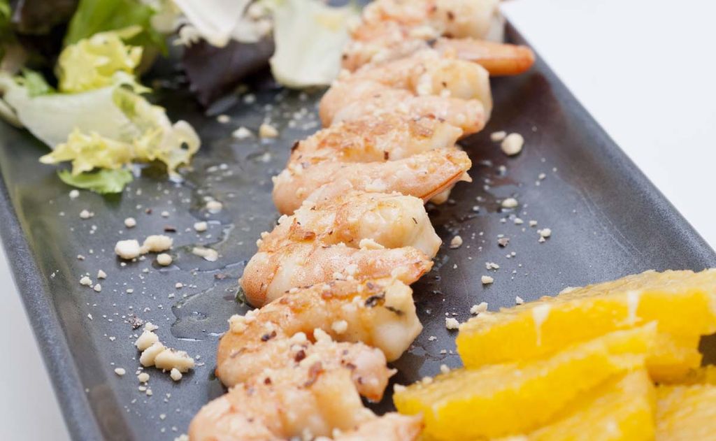 Brocheta de langostinos y coco con vinagreta de naranja