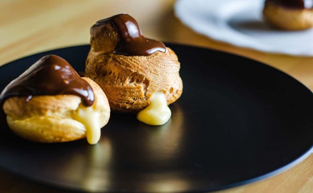 Profiteroles rellenos de crema pastelera con chocolate caliente