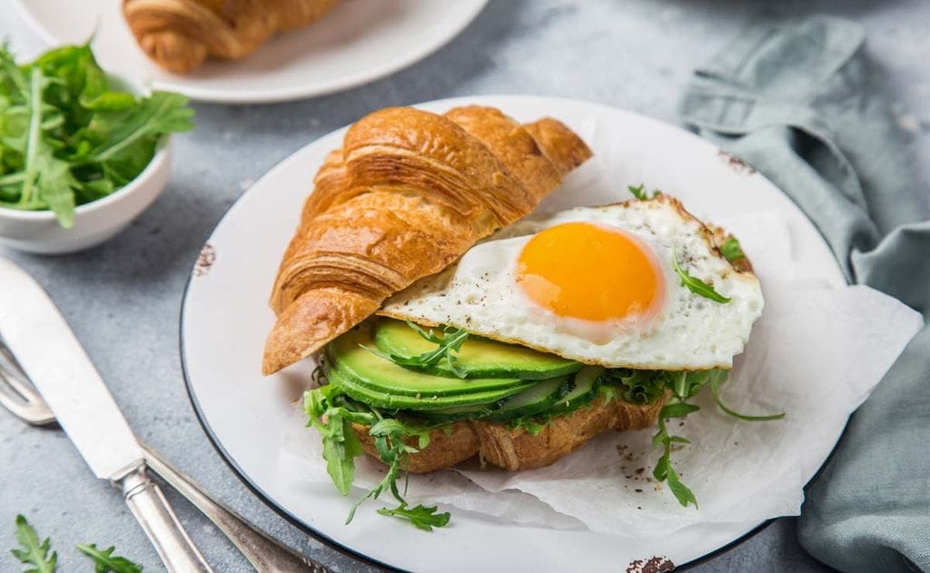 Cruasán con rúcula, aguacate y huevo a la plancha