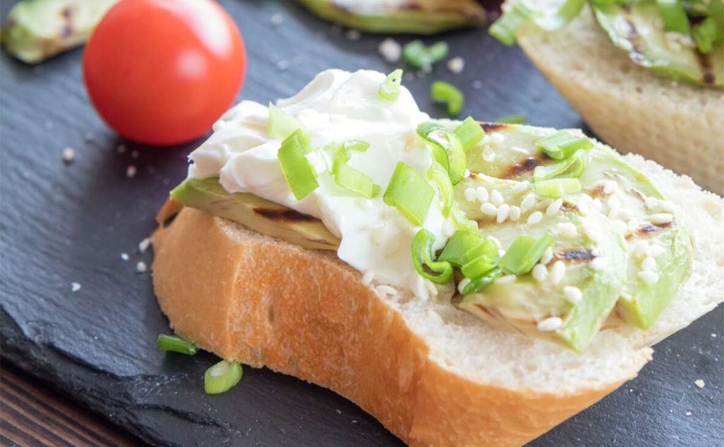 Tostas de aguacate a la parrilla con queso crema, cebolleta y sésamo