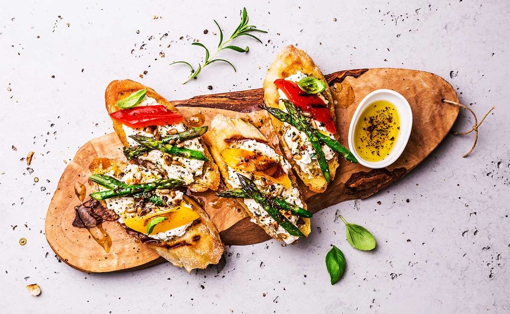 Tostas de queso, espárragos y pimientos con piñones