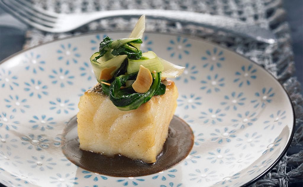 Taco de bacalao con acelgas y almendras sobre emulsión de ajo negro