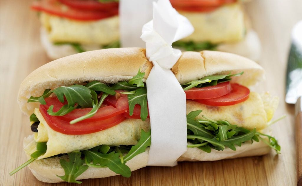 Bocadillo de tortilla y queso con rúcula y tomate