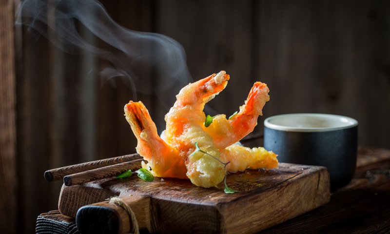 Tempura de verduras y gambas presentadas en una tabla de madera