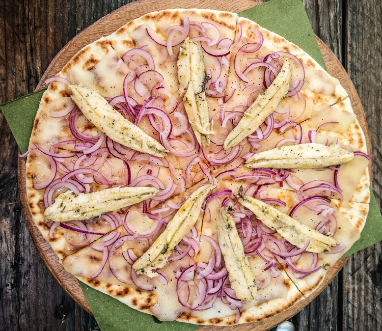 Pizza con base de piadina, boquerones y cebolla morada