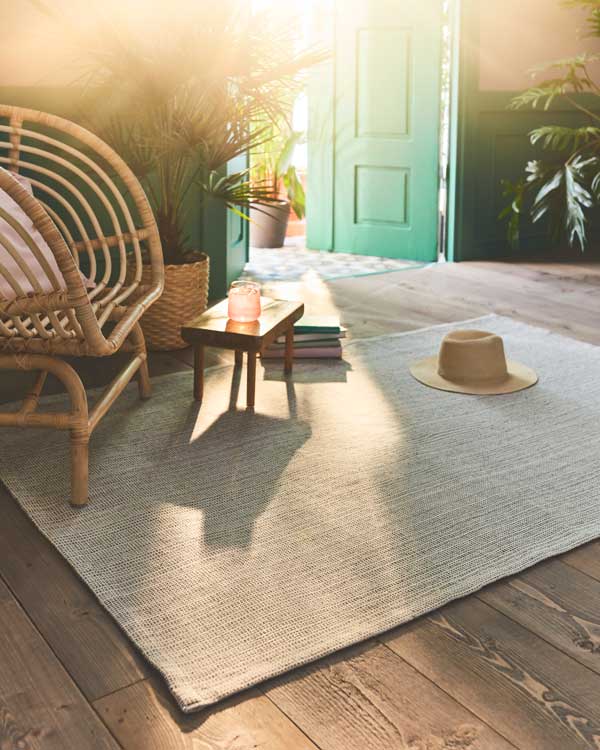 Rincón de relax con sillón de fibras vegetales, plantas y alfombra