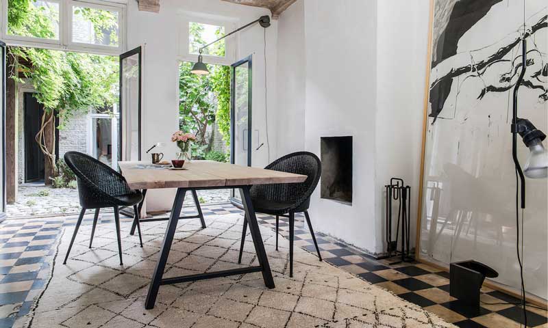 Comedor con salida al jardín, decorado con mesa de madera, sillones negros y alfombra XL