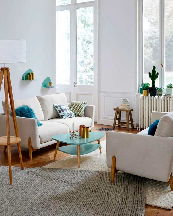 Salón contemporáneo con suelo de madera, sofás blancos y cojines y accesorios en color azul