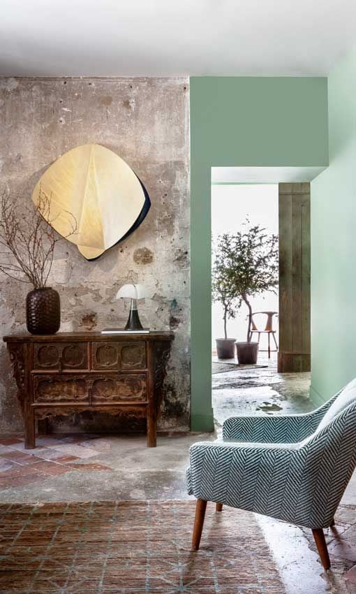 Recibidor con paredes verdes, suelos y revestimientos 'Wabi shabi' y aparador 'vintage