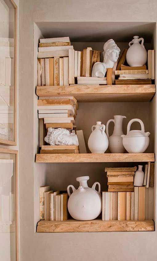 Detalle de librería empotrada con baldas de madera artesanales, libros y objetos de cerámica