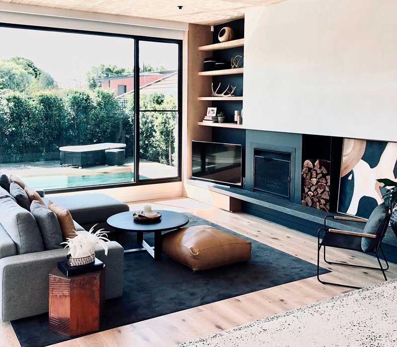 Salón de estilo moderno con salida al jardín, chimenea tipo cassette y sofá y alfombras grises